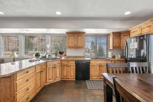 Kitchen with black appliances, recessed lighting, a sink, and light stone countertops