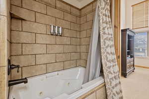 Bathroom with a combined bath / shower with jetted tub and baseboards