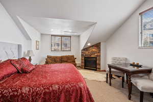 Carpeted bedroom featuring a stone fireplace and a textured ceiling