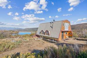 View of side of home with a gambrel roof and a water and mountain view