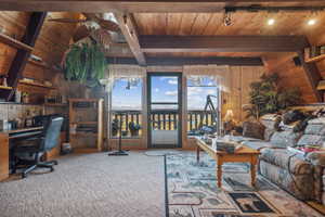 Carpeted living room with wood ceiling, wood walls, and vaulted ceiling with beams