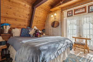 Bedroom featuring lofted ceiling, wooden walls, and wood ceiling