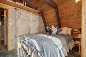 Bedroom with wooden ceiling and vaulted ceiling with beams