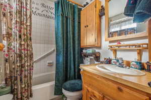 Bathroom featuring toilet, vanity, and shower / bathtub combination with curtain