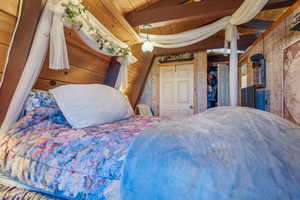 Bedroom featuring beamed ceiling and wooden walls