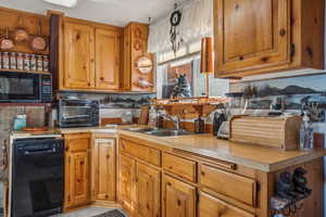 Kitchen with a toaster, a sink, black appliances, light countertops, and brown cabinets