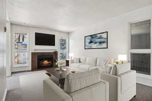 Carpeted living area with a fireplace and a textured ceiling