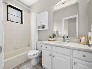 Bathroom featuring shower / tub combo with curtain, toilet, and vanity
