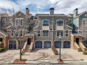 Multi unit property with stucco siding, a garage, driveway, and a chimney