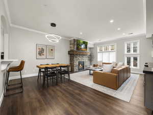 Living area featuring wood finished floors, a fireplace, baseboards, and ornamental molding