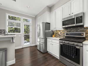 Kitchen featuring white cabinetry, light countertops, dark wood-style flooring, and stainless steel appliances
