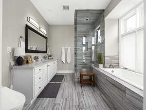 Full bathroom featuring visible vents, a garden tub, a stall shower, baseboards, and vanity