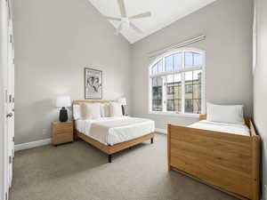 Carpeted bedroom with high vaulted ceiling, baseboards, and ceiling fan