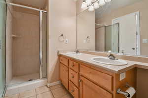 Bathroom featuring a stall shower, a sink, and tile patterned floors