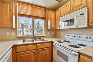 Kitchen featuring light countertops, white appliances, and a sink