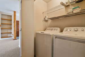 Laundry room with laundry area, separate washer and dryer, carpet, and built in features