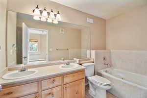 Bathroom with toilet, visible vents, a sink, and a bath