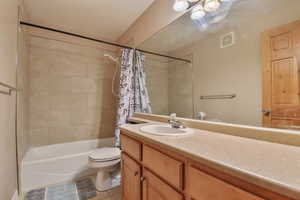 Full bath featuring tile patterned flooring, toilet, vanity, visible vents, and shower / bath combo