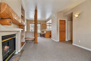 Unfurnished living room featuring visible vents, baseboards, a fireplace with flush hearth, dark carpet, and a sink