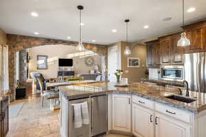 Kitchen with open floor plan, stone tile floors, appliances with stainless steel finishes, arched walkways, and a sink