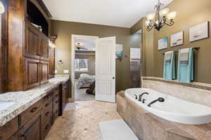 Bathroom with tiled shower, double vanity, a sink, a garden tub, and connected bathroom