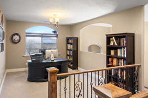 Carpeted office with baseboards and a chandelier