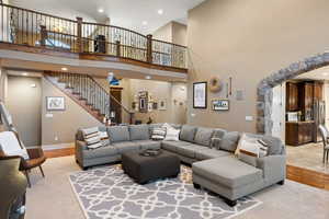 Living room featuring stairway, baseboards, a high ceiling, recessed lighting, and light wood-style floors