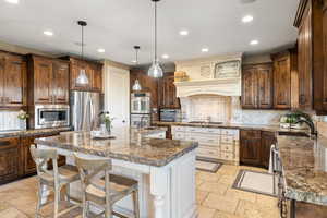 Kitchen with stone tile floors, recessed lighting, stainless steel appliances, and a sink