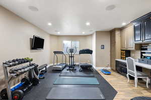 Workout room with recessed lighting, built in study area, baseboards, and light wood-style floors