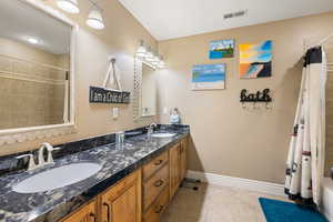 Bathroom featuring a sink, visible vents, baseboards, and tile patterned flooring