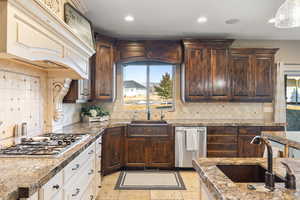 Kitchen featuring a sink, custom range hood, dark brown cabinets, and stainless steel gas cooktop