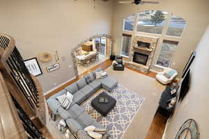 Living room featuring ceiling fan, baseboards, a towering ceiling, and a fireplace