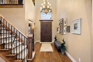 Foyer entrance featuring a chandelier, baseboards, hardwood / wood-style floors, and stairs