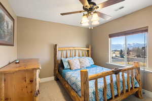 Carpeted bedroom featuring visible vents, ceiling fan, a mountain view, and baseboards