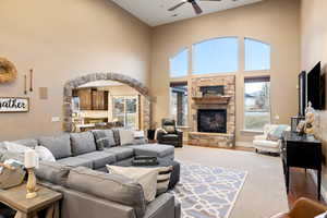 Living room featuring arched walkways, a stone fireplace, wood finished floors, and a healthy amount of sunlight