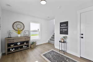 Entryway featuring stairway, baseboards, and wood finished floors
