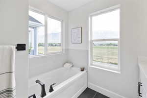 Full bathroom featuring tile patterned flooring, a mountain view, baseboards, and a garden tub