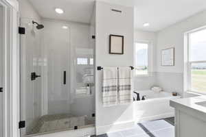 Bathroom featuring tile patterned flooring, a garden tub, visible vents, and a wealth of natural light
