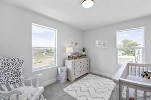 Bedroom with baseboards, multiple windows, and light carpet