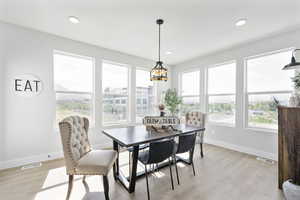 Dining room featuring light wood-type flooring, visible vents, and plenty of natural light