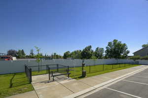View of property's community with a gate, uncovered parking, a yard, and fence
