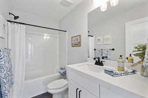 Full bathroom with vanity, shower / bath combination with curtain, and toilet