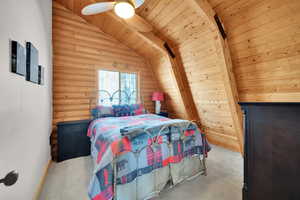 Bedroom featuring wood ceiling, rustic walls, vaulted ceiling with beams, and carpet flooring