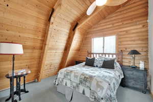 Bedroom featuring a ceiling fan, carpet, log walls, wood ceiling, and vaulted ceiling with beams