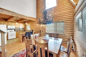 Dining area with beam ceiling, light wood-type flooring, and a high ceiling