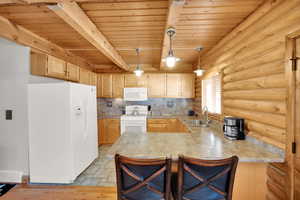 Kitchen with white appliances, visible vents, a peninsula, a sink, and wooden ceiling