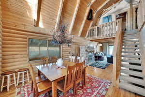 Dining space with high vaulted ceiling, wood ceiling, wood finished floors, and stairs