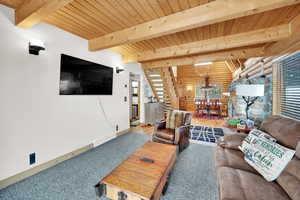 Living room featuring stairway, baseboards, visible vents, log walls, and beam ceiling