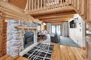 Unfurnished living room featuring baseboards, wood ceiling, beam ceiling, a fireplace, and wood finished floors