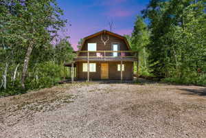 Back of property at dusk featuring a gambrel roof